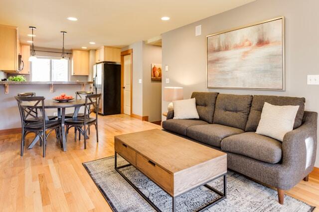 an open concept living room and kitchen with light wood